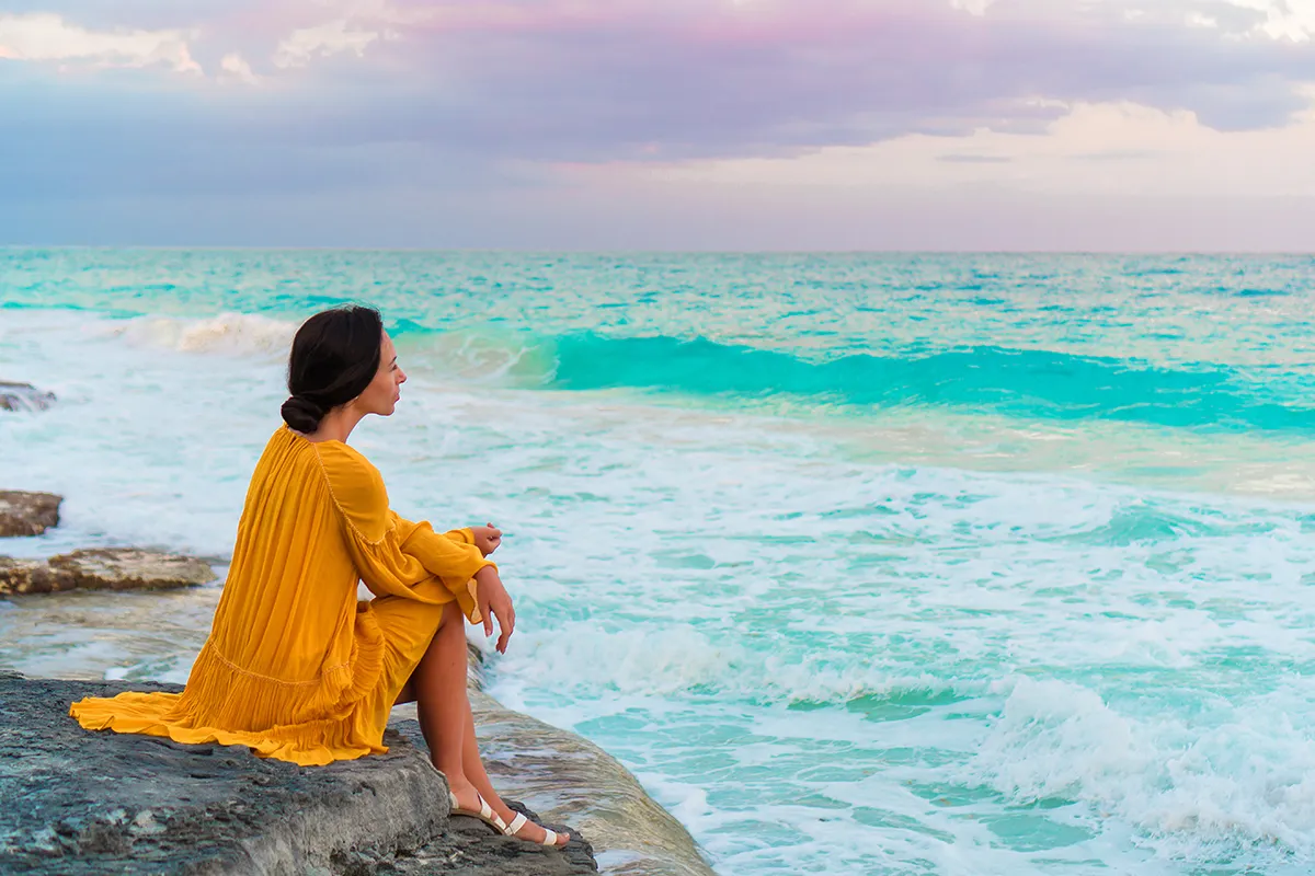 Young beautiful woman in sunset. Happy girl in dress in the evening on the beach