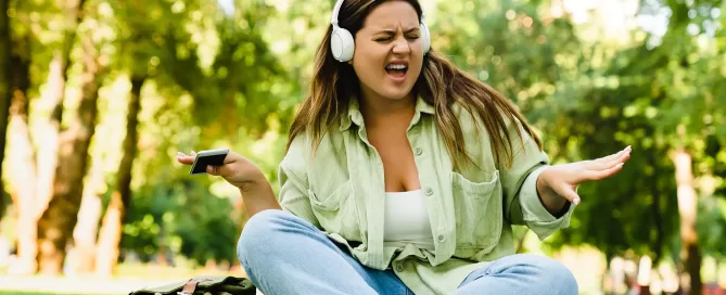 Dancing woman relaxing after college university listening to the music in headphones in campus park